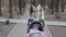 Family, motherhood and people concept - mother with baby girl sleeping in stroller walking at spring park