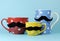 A family of mustaches on blue, red and yellow polka dot coffee and tea cups and mugs