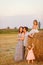 Family near haystacks on sloping field village.