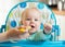 Family and nutrition concept - mother spoon feeding little baby sitting in highchair at home