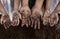 Family parent and children showing dirty hands after planting the tree together