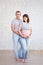 family and parenthood concept - full length portrait of cute pregnant couple over white brick wall