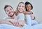 Family, parents and child in interracial portrait on bed with smile, love or happy bonding together in home. Bedroom