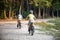 Family in the park on bicycles. two sibling brothers kids boys compete in riding. view from back