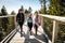 Family people walking wooden treetop bridge canopy walkway in winter