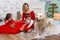Family photo portrait. Mom and her two children and two white dogs in red clothes celebrate the Chistmas, new year