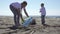 Family picks up trash from the beach in trash bags