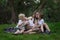 Family picnic at garden outdoors. Mother and three children sitting on picnic blanket in the Park. Mom kisses son