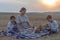 Family picnic in nature. mother and children eat on a sloping wheat field