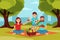 Family on picnic in park. Parents sitting on blanket, kid holding ball. Green trees, bushes and city buildings on