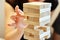 Family play board game. Hands take wooden block from tower.