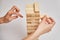 Family play board game. Hands take wooden block from tower.