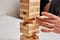 Family play board game. Hands take wooden block from tower.