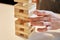 Family play jenga. Hands take wooden block from tower.