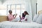 Family playing clapping games on bed in bedroom