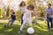 Family Playing Soccer In Park Together