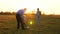 Family playing with younger baby with soccer ball in the park at sunset. Happy dad and child kick ball. happy family