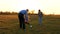 Family playing with younger baby with soccer ball in the park at sunset. Happy dad and child kick ball. happy family