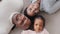 Family portrait african american parents with little daughter girl child lying on floor looking smiling, adult mature