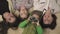 Family portrait of cheerful older sisters and younger boy and girl lying on the carpet in the room. Funny little boy in