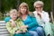 Family portrait with mother, young son and senior grandmother sitting together on bench at summer park