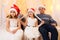 Family portrait - parent and children in home interior decorated with holiday lights and gifts, dressed in santa hat for new year