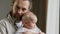 Family portrait serious Caucasian bearded dad father man holding hugging small infant newborn girl boy kid daughter son