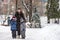 Family portrait of a smiling mother hugging a boy and his sibling brother. Wearing winter warm clothes walking winter city streets