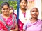 Family portrait of a Young Indian dalit women wearing colored saree with her sister and grand mother posing in the street of the