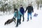 Family Pulling Sledge Through Snowy Landscape