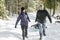 Family Pulling Sledge Through Snowy Landscape