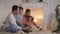 Family read book sitting on sofa in front of fireplace in Christmas decorated house interior