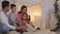 Family read book sitting on sofa in front of fireplace in Christmas decorated house interior