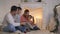 Family read book sitting on sofa in front of fireplace in Christmas decorated house interior