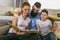 Family reading storybook at home in the living room