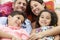 Family Relaxing In Garden Hammock Together