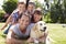 Family Relaxing In Garden With Pet Dog