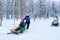 Family riding on husky dogs sledge and snowmobile in Rovaniemi