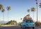 Family road trip by blue car with luggage bags on roof in tropical landscape, AI generated