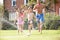 Family Running Through Garden Sprinkler