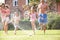 Family Running Through Garden Sprinkler