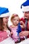 Family in Santa\'s hat sitting in artificial snow