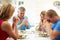 Family Saying Prayer Before Eating Meal At Home Together