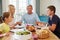 Family Saying Prayer Before Enjoying Meal At Home Together