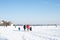 A family on the school run in a snowy field under a blue clear sky