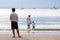 Family on the sea. A father watches his wife and son enter the water from the sandy beach