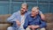 Family of senior father and adult son or grandson having conversation chatting relaxing on couch