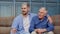 Family of senior father and adult son or grandson having conversation chatting relaxing on couch