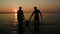 Family silhouettes coming out of sea at sunset