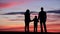 Family silhouettes portrait at sunset, parent and child hold hands, invincible